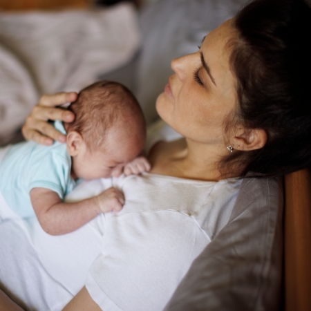 Exhausted mother holding her crying newborn baby. Postpartum depression.